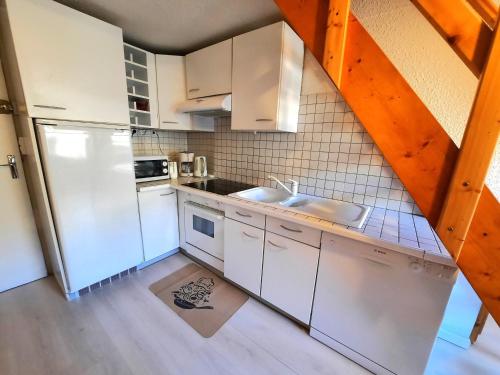 une cuisine avec des armoires blanches et un réfrigérateur blanc dans l'établissement Charmant duplex 6 pers. au pied des pistes avec balcon et mezzanine - Les Menuires - FR-1-452-119, aux Menuires