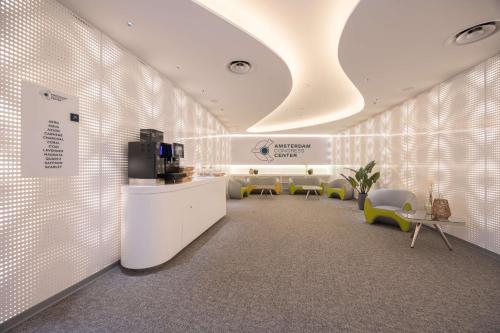 a lobby with a waiting room with chairs and a television at Park Inn by Radisson Amsterdam City West in Amsterdam