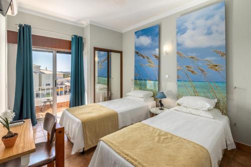 a bedroom with two beds and a view of the ocean at Guest House Oliveira in Boliqueime