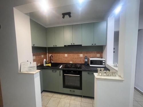 a kitchen with green cabinets and a stove top oven at Apartament Zarnesti in Zărneşti