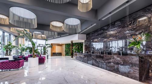 a lobby with purple chairs and plants at Grand Hotel Adriatic II in Opatija