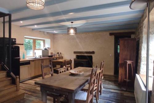 a dining room with a table and a kitchen at Maison dans la campagne bretonne in Glomel