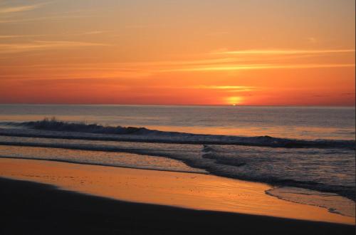 a person walking on the beach at sunset at Pool View in Pawleys Island in Pawleys Island