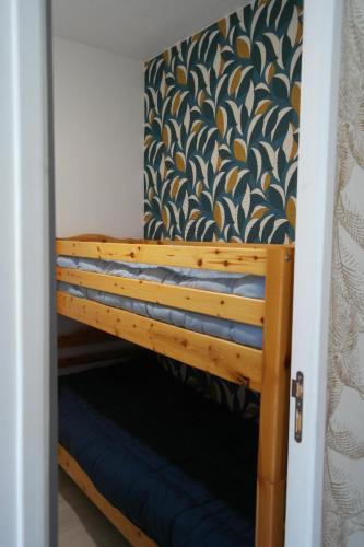 Ce lit superposé se trouve dans un dortoir revêtu de papier peint. dans l'établissement Appartement climatisé avec terrasse parking piscine et terrains de tennis, au Cap d'Agde