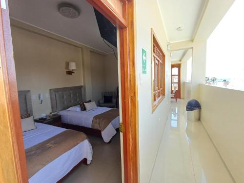 a hotel room with two beds and a hallway at Arena Hostal in Paracas