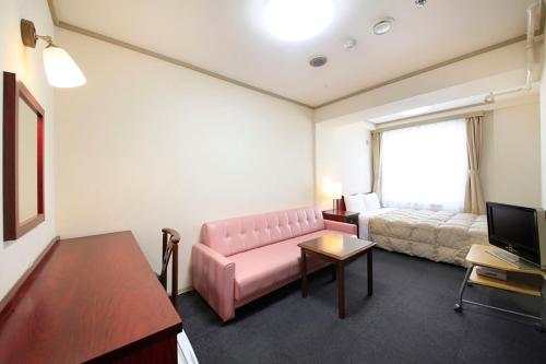 a living room with a pink couch and a bed at Shinjuku Urban Hotel in Tokyo