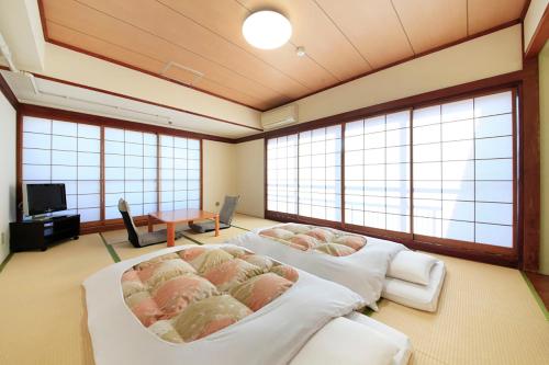 two beds in a room with large windows at Shinjuku Urban Hotel in Tokyo
