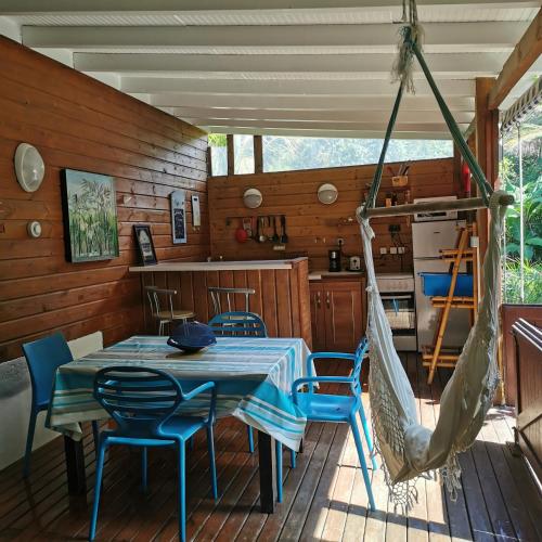 a porch with a hammock and a table and chairs at Gîte 1001 Nuits - SINBAD in Bouillante