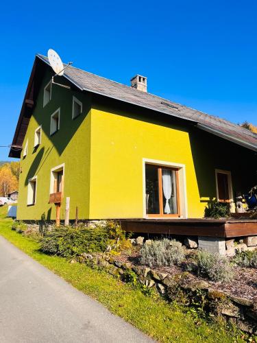 ein gelbes und grünes Haus am Straßenrand in der Unterkunft Chalupa U Franze in Malá Morava