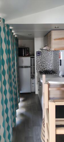Il comprend une cuisine équipée d'un comptoir et d'une cuisinière. dans l'établissement Mobile home 6 personnes Valras plage, à Valras-Plage