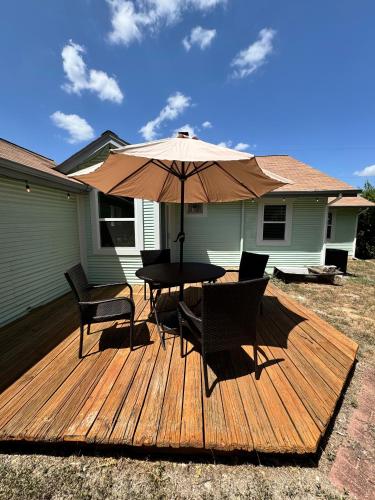 a wooden deck with a table and chairs and an umbrella at Lovely Home Away From Home - Entire House! in Austin