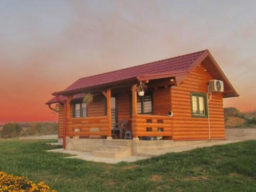 a cabin in a field with a sunset in the background at Brvnara Staničić in Arandjelovac