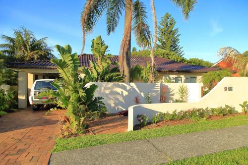 a house with palm trees and a white fence at Cronulla Beach House B&B in Cronulla