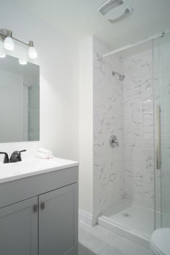 a white bathroom with a shower and a sink at Montfort Hotel in Ottawa