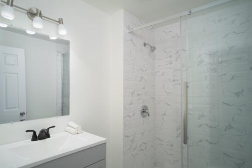 a white bathroom with a shower and a sink at Montfort Hotel in Ottawa