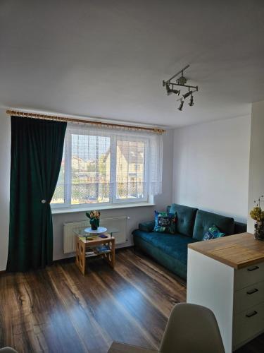a living room with a blue couch and a table at Apartament w Suwałkach in Suwałki