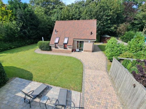 a house with two chairs and a brick walkway at Koperwiek Texel in Den Burg