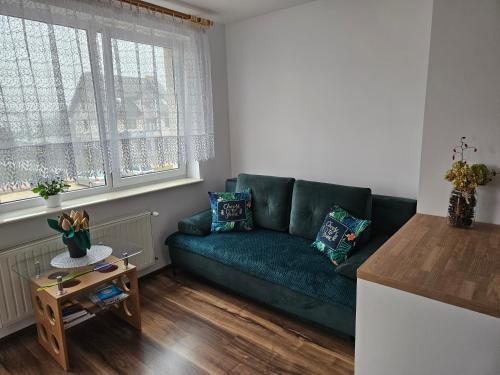 a living room with a green couch and a table at Apartament w Suwałkach in Suwałki