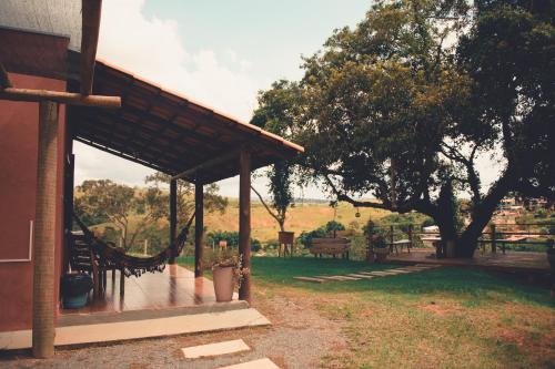 a porch of a house with a tree and benches at Pousada Chalés do Rancho Canastra in Vargem Bonita