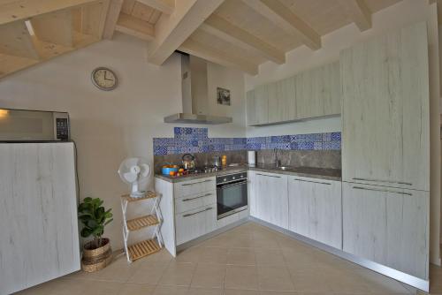 a kitchen with white cabinets and blue tiles at Casa Rita Fonteno in Fonteno