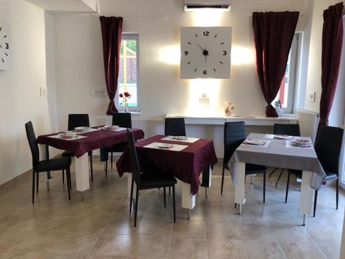 a dining room with tables and a clock on the wall at Gavriel Boutique Residence Wellness Spa in Szada