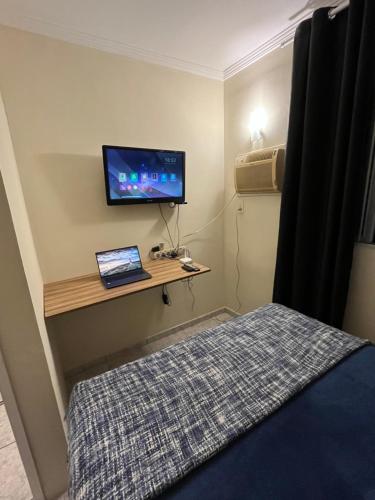 een slaapkamer met een bed en een bureau met een televisie bij Apt Central Caraguá in Caraguatatuba