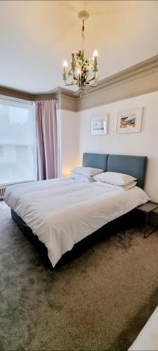 a bedroom with a large bed with a chandelier at Time & Tide Town House in Seaford