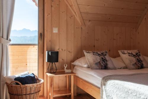una camera da letto con un letto in una camera in legno con finestra di Domki WIDOKÓWKA -domki z balią na wyłączność a Bukowina Tatrzańska