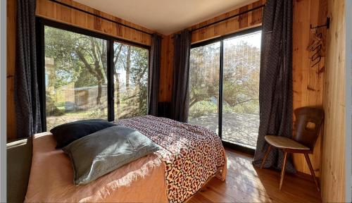 - une chambre avec un lit dans une pièce dotée de grandes fenêtres dans l'établissement Maison bois avec vue lac Piscine, à Teillet
