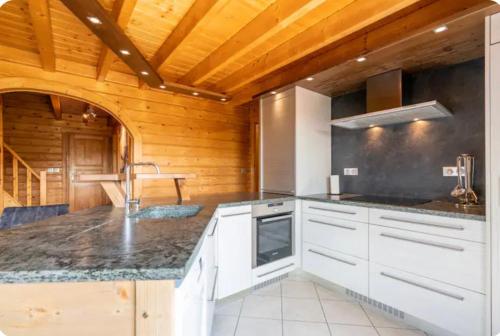 une cuisine avec des armoires blanches et un plafond en bois dans l'établissement Chalet Solie, à La Bresse