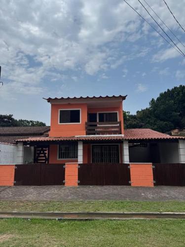 an orange house with a fence in front of it at Casa Praia Riviera São Lourenço in Bertioga