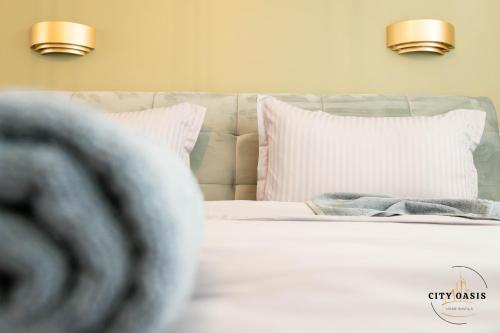 a bedroom with a bed with white sheets and pillows at City Oasis Villa in Sibiu in Sibiu