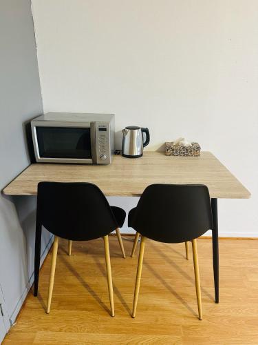 une table en bois avec deux chaises et un four micro-ondes dans l'établissement Studio 6 Proche Centre Ville avec Wifi Parking Troyes, à Troyes