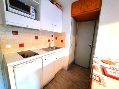 une cuisine avec un évier et un micro-ondes dans l'établissement Charmant appartement 4 pers avec balcon, skis aux pieds, Les Menuires - FR-1-452-31, aux Menuires