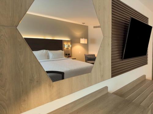 a hotel room with a bed and a flat screen tv at Holiday Inn Express Mérida by IHG in Mérida