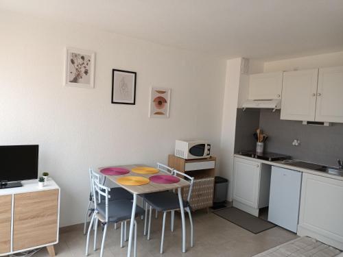 une cuisine avec une table et des chaises dans une cuisine dans l'établissement Appartement proche port village et plage, à Gruissan