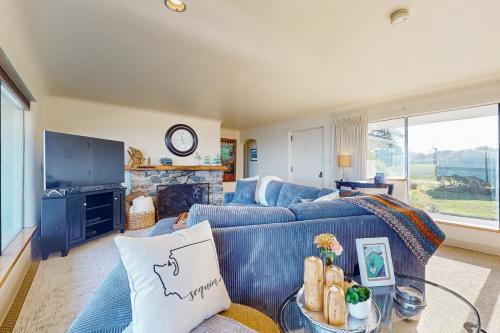 a living room with a blue couch and a fireplace at Windrift House in Sequim