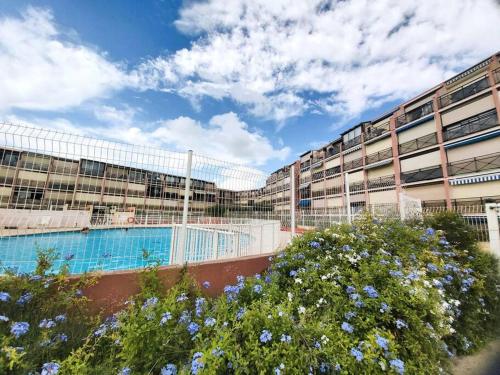 un grand bâtiment avec une piscine devant dans l'établissement Appartement proche du Casino et Séquarium, au Grau-du-Roi