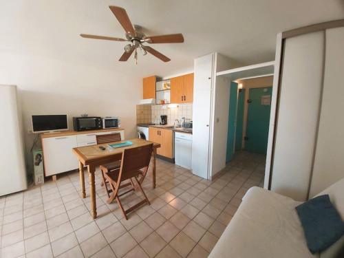 une cuisine avec une table et un ventilateur de plafond dans l'établissement Appartement proche du Casino et Séquarium, au Grau-du-Roi