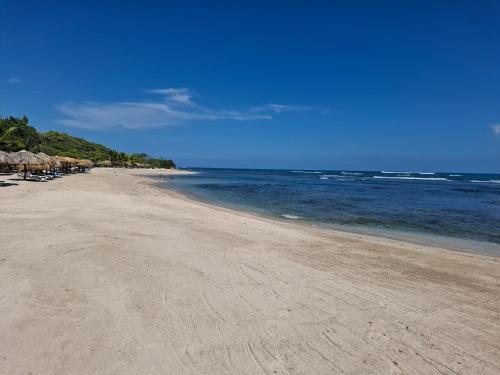 a sandy beach with umbrellas and the ocean at Costambar Ocean Breeze - Beachfront Apartment with Pool in Las Flores