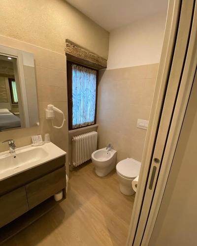 a bathroom with a sink and a toilet and a window at Agriturismo San Pellegrino in Fermignano