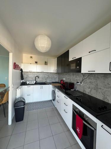 une cuisine avec des armoires blanches et des comptoirs noirs dans l'établissement Bel appartement à Bordeaux Lac, à Bordeaux