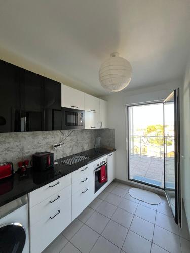 une cuisine avec des placards blancs et une grande fenêtre dans l'établissement Bel appartement à Bordeaux Lac, à Bordeaux