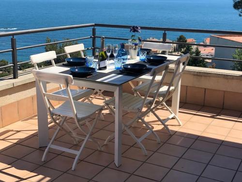 a table with chairs and wine bottles on a balcony at Sensational Apartment with panoramic views in Llança