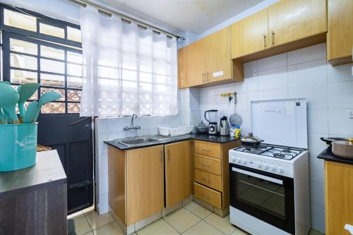 a kitchen with wooden cabinets and a white stove top oven at Hirwado Homes - With 5 Beds, 2Baths & Balcony in Nairobi
