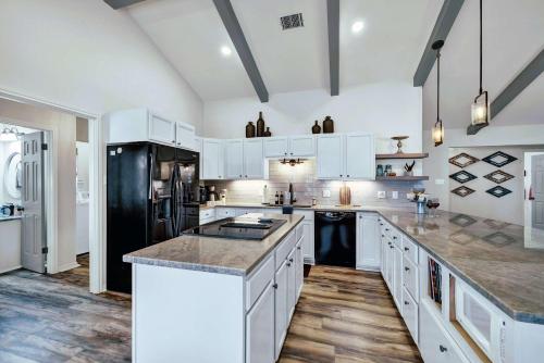 a kitchen with white cabinets and a black refrigerator at Peach Street Retreat - Fire Pit and Close to Main St in Fredericksburg