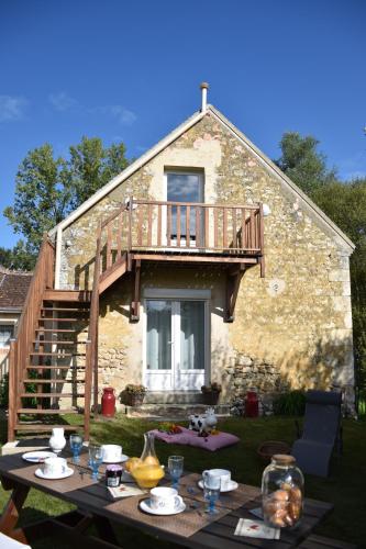 a table in front of a house with a balcony at Gîte des Comtes du Perche 2 logements indépendants de 40 et 25 m2 in Val-au-Perche