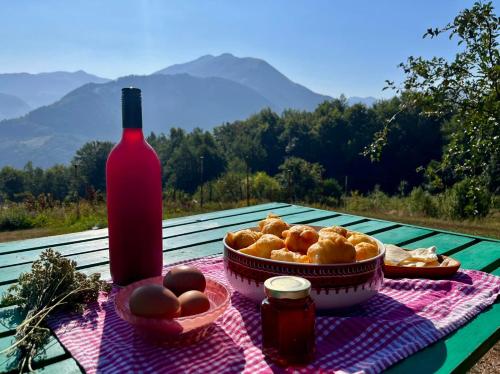 a table with a bottle of wine and a basket of bread at Kolibe Ćorić in Mojkovac