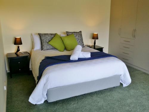 a bedroom with a large white bed with green pillows at Beaulieu in Coles Bay
