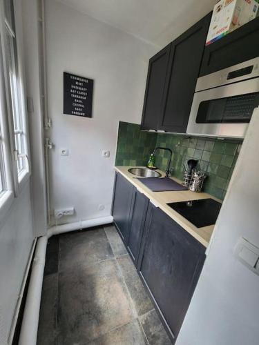 une petite cuisine avec un évier et un réfrigérateur dans l'établissement Cosy T2 proche Basilique Saint Denis, à Saint-Denis